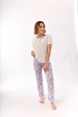 Pijama compuesto por una remera blanca de manga corta con cuello redondo y cartera de botones con ribete estampado, y un pantalón largo con estampado tropical de hojas y sandías sobre fondo blanco.