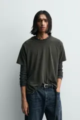 Camiseta relaxed fit color gris oscuro, confeccionada en tejido ligero de algodón con elasticidad. Presenta cuello redondo y manga ranglán corta.