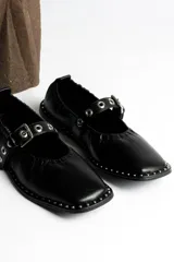 Ballerinas negras de cuero con correa sobre el empeine, hebilla metálica y tachas plateadas.