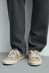 Zapatilla de cordones para hombre, fabricada en piel con acabado serraje (gamuza) color beige claro. Presenta detalles de pespuntes y una suela gruesa de goma a contraste en color crema.