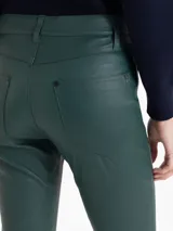 Pantalón de cuero ovino elastizado en color verde oscuro, con silueta levemente oxford, cierre metálico, botón jeanero y bolsillos delanteros y traseros.