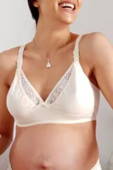 Soutien maternal color crema, sin aro, confeccionado en algodón con detalles de puntilla. Cuenta con broche especial para amamantar y breteles elásticos regulables.