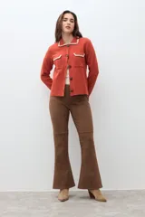 Chaqueta tejida de punto color naranja, con cuello camisero, cierre frontal de botones y dos bolsillos frontales con solapa. Presenta detalles de bordado en contraste en el cuello y los bolsillos.