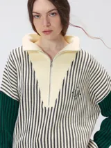 Pullover de tejido acanalado grueso con diseño bicolor en tonos marrón y bordó. Presenta cuello alto con cierre frontal, mangas largas y corte holgado.