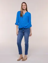 Blusa de calce relajado color salmón, confeccionada en tela liviana con textura sutil. Presenta escote en V con abotonadura frontal, bolsillo parche en el pecho, mangas largas regulables con presilla y ruedo con opción de anudar en el frente.