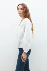 Blusa blanca de manga larga con escote en V y bordados en el frente.