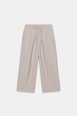 Pantalón de tiro medio color beige, con cintura elástica ajustable con cordones. Cuenta con bolsillos laterales ocultos en la costura y bolsillos de plastrón en la espalda.