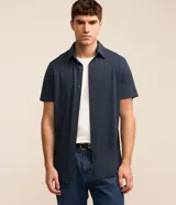 Camisa de manga corta azul marino, de corte recto con cuello camisero y cierre frontal de botones.