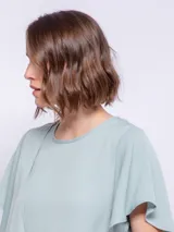 Top rosado de mangas cortas con volados, cuello redondo y detalle diagonal en el frente.