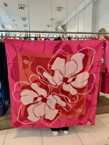 Pañuelo cuadrado grande de tela suave color rosa con estampado floral en tonos rojo y blanco.