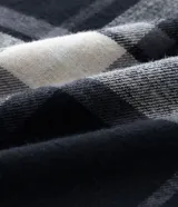 Pantalón de pijama de corte recto confeccionado en franela de algodón con estampado de cuadros en tonos blanco y negro. Presenta cintura elástica con cordón de ajuste para mayor comodidad.
