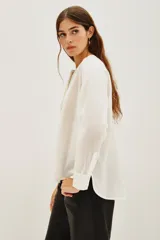 Camisa de algodón color blanco, con cuello redondo, cierre frontal parcial con botones y detalle de bordado con canutillos en el frente.