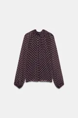 Blusa de manga larga con cuello subido y detalle de lazo en la espalda. Presenta un diseño plisado con estampado de lunares y forro interior.