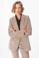 Blazer de corte sastrero en color beige, con cuello solapa, cierre frontal y bolsillos ojal. Presenta una textura suave y diseño estructurado.