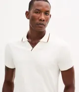 Camisa polo de manga corta confeccionada en algodón, con cuello en V y detalles en color contrastante en el cuello y los puños. Presenta un diseño de tejido en media malla, ofreciendo una textura suave y transpirable.
