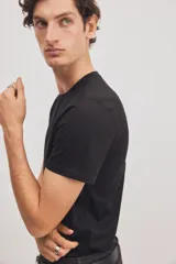 Remera negra de corte ajustado en punto suave de algodón pima, con cuello redondo ribeteado acanalado fino y bajo recto.