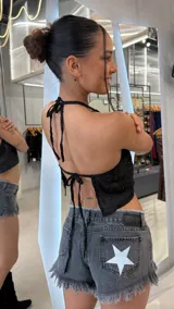 Top halter negro con escote redondo y tiras finas para anudar al cuello, confeccionado con tela transparente bordada de diseño floral y detalles de lentejuelas.