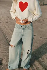 Jeans de tiro medio y corte ancho, confeccionados en denim con lavado estilo vintage de efecto desgastado. Presentan diseño de doble cinturilla superpuesta, cinco bolsillos tradicionales, trabillas para cinto y cierre frontal con cremallera y botón metálico.
