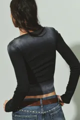 Camiseta de manga larga color negro con efecto lavado, cuello barco y detalle de tachas plateadas distribuidas por todo el frente.