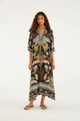 Vestido largo negro con estampado multicolor de inspiración tropical y geométrica, escote en V, mangas tres cuartos amplias y cordón ajustable en la cintura.
