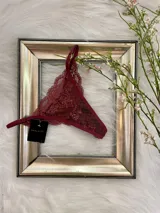 Pack de tres bombachas tipo tanga con diseño de encaje y tiras ajustables. El set incluye modelos en colores bordó, negro y blanco, confeccionados con detalles de encaje floral y terminaciones delicadas.
