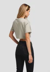 Remera cropped de algodón, color gris claro, con cuello redondo y manga corta doblada. Presenta un estampado frontal de un plátano amarillo.