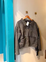 Campera verde militar de gamuza sintética, con flecos en el frente y en la espalda.