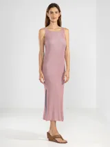 Vestido midi sin mangas, confeccionado en punto jersey con hilo Lurex que aporta un brillo sutil. Presenta escote bote redondeado y aberturas laterales en el ruedo.