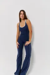 Mono deportivo largo de una pieza, color azul marino con detalles de líneas blancas verticales que recorren el torso y las piernas. Presenta escote redondo y espalda estilo nadador.
