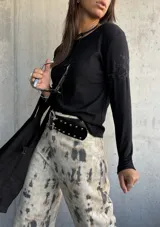 Remera de manga larga color negro, con cuello redondo y detalle de bordado floral sutil en el hombro. Confeccionada en algodón, presenta un corte ajustado y versátil.