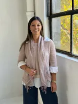 Sweater de punto rosa claro con diseño de capas, que incluye una camisa blanca debajo y un pañuelo a juego con detalles de encaje y flecos en el ruedo.