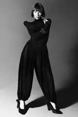 Mono largo negro con cuello subido y manga larga ajustada. El cuerpo superior es liso y ajustado, mientras que la parte inferior es de pantalón ancho con mucho volumen y frunces, ajustado en el tobillo con una lazada.