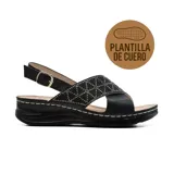 Sandalia negra con plataforma baja y plantilla de cuero. Presenta una tira ancha sobre el empeine con apliques brillantes y una tira trasera con hebilla ajustable.