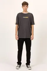 Remera oversize Billabong de color negro, con cuello redondo en tono beige y detalles de bandas beige en los hombros y mangas. Cuenta con un pequeño estampado frontal con el logotipo de la marca.