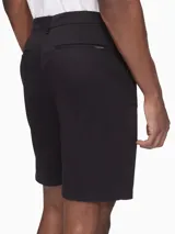 Short negro de corte chino, con bolsillos laterales y traseros, cierre con cremallera y botón, trabillas para cinturón y logo bordado.