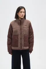 Campera de diseño híbrido que combina paneles de corderito en el frente y cuello con mangas y laterales de tela acolchada con costuras onduladas. Presenta cierre frontal completo, bolsillos laterales y un pequeño parche decorativo en el pecho.