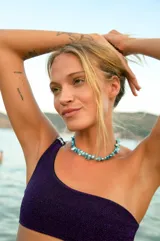 Conjunto de bikini violeta de tela lúrex, con corpiño de un hombro con hebilla y bombacha vedetina.