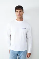 Camiseta de manga larga color blanco, con cuello redondo y estampado pequeño en el pecho con la frase 'Comfy Cooking'.