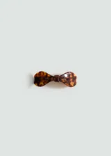 Hebilla para el pelo con diseño de lazo en estampado carey, fabricada en acetato con cierre metálico a presión.