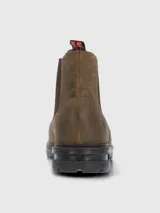 Bota estilo Chelsea color marrón, confeccionada en cuero con paneles elásticos laterales en tono marrón oscuro. Presenta una suela de goma robusta y flexible con tecnología de absorción de impactos y una tira decorativa en la parte trasera con diseño de bandera.