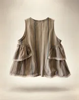 Blusa sin mangas de diseño fluido, confeccionada en tejido gris con rayas verticales finas. Presenta cuello redondo, cierre frontal con botones y detalles de volados escalonados en los laterales con terminaciones en puntilla blanca.