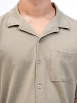 Camisa de manga corta color beige, confeccionada en tejido piqué de algodón, con cuello cubano y un bolsillo de parche en el pecho.