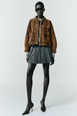 Falda pantalón de tiro alto con diseño de tablas, confeccionada en tejido gris. Incluye un cinturón fino de cuero sintético con hebilla metálica dorada y cierre lateral con cremallera oculta.