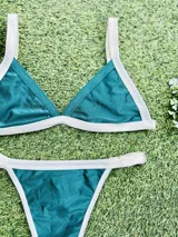 Conjunto de bikini verde esmeralda con ribetes blancos, compuesto por un corpiño triangular fijo con abertura para agregar tazas soft y una bombacha colaless regulable.