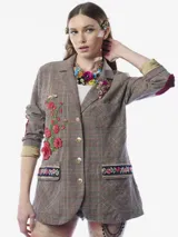 Blazer de corte sastre con estampado de cuadros en tonos grises y líneas rojizas. Presenta detalles bordados de flores con lentejuelas en el frente, parches en los codos, solapa clásica y cierre frontal con botones metálicos. Incluye bolsillos con solapas decoradas con bordados florales y un broche floral con cristales en la solapa.
