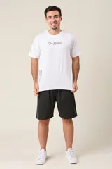 Bermuda deportiva negra de nylon, corte suelto, con cintura elástica, cordón de ajuste, líneas en los costados y bolsillos con cierre.