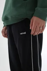 Pantalón de jogging negro de felpa con corte recto, tiro medio, línea lateral blanca y logo VERNAL bordado.