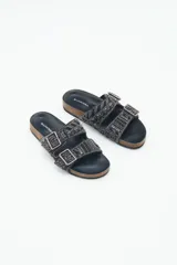 Sandalia baja abierta de estilo 'slide' con dos tiras ajustables con hebillas metálicas. Las tiras están completamente decoradas con bordados de mostacillas, canutillos y strass en tonos negros y grises. La plantilla es de corcho visible forrada en cuero negro, y la suela es de goma.