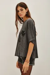 Remera de corte holgado y mangas cortas, confeccionada en tejido gris con efecto lavado. Presenta una estampa frontal con la frase 'Start Me Up' realizada en lentejuelas negras.