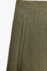 Pantalón de lino negro, de tiro alto, con bolsillos delanteros de vivo, pernera recta y cierre frontal con cremallera, botón interior y gancho metálico.